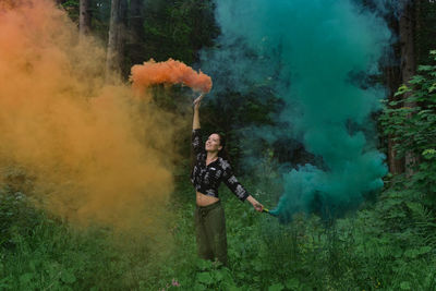 Woman standing in a forest with color smoke
