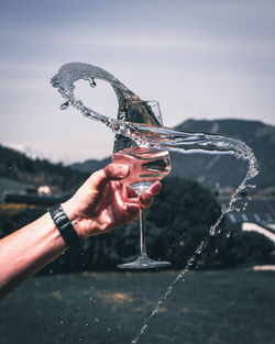 Close-up of hand holding glass splashing water