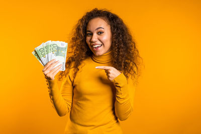 Portrait of a smiling young woman against yellow background