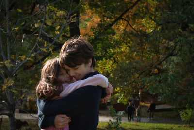 Side view of siblings embracing at park