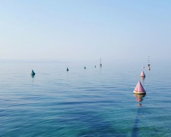 Buoys floating in sea against clear sky