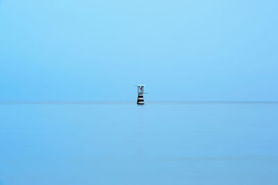 Boat sailing on sea against clear blue sky