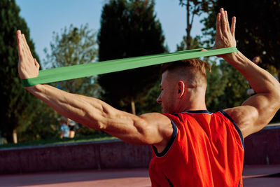 Rear view of man exercising on field