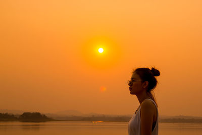 Woman standing against lake during sunset