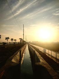 Bridge over canal against sky during sunset