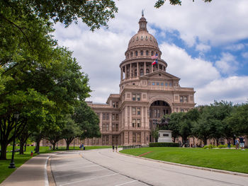 The texas state capitol with waving american and texan flags on a sunny summer day in austin, texas.