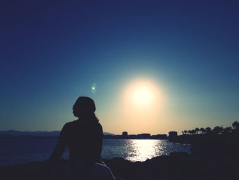 Silhouette woman on beach against sky during sunset