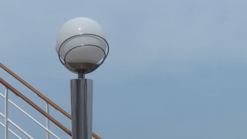 Low angle view of lighting equipment by railing against sky