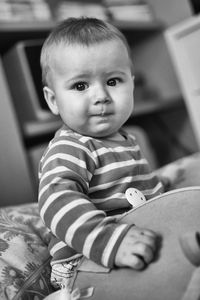 Portrait of baby boy sitting on bed at home