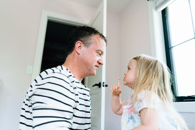 Side view of a toddler motioning for her dad to be quiet