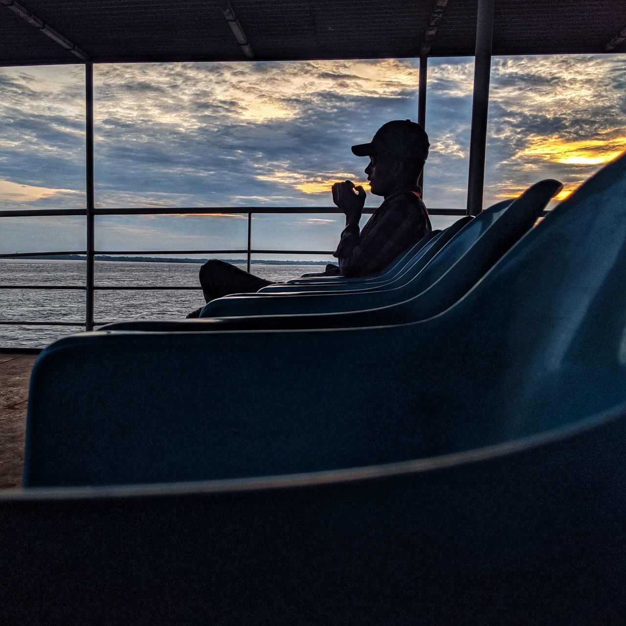 transportation, mode of transportation, real people, window, sitting, cloud - sky, sky, leisure activity, glass - material, lifestyles, nautical vessel, one person, nature, vehicle interior, men, transparent, travel, outdoors, sunset