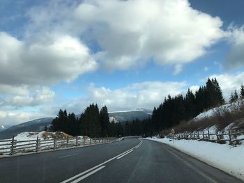 Road amidst trees against sky