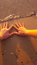 Close-up of hands on sand at beach