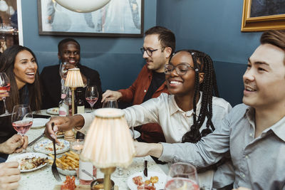 Multiracial female and male friends having food at table in restaurant