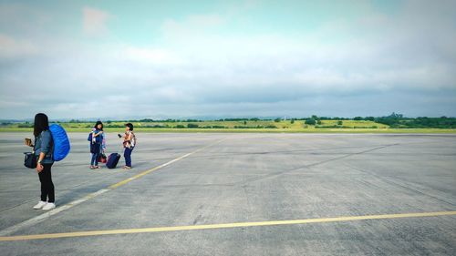Rear view of people walking on road against sky