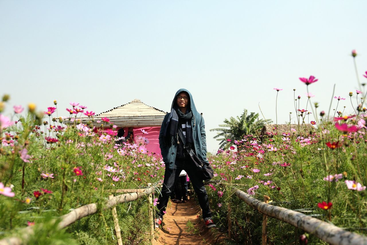 lifestyles, full length, flower, casual clothing, leisure activity, young adult, clear sky, standing, young women, rear view, person, walking, plant, long hair, copy space, built structure, dress