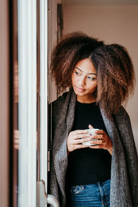 Portrait of young woman holding camera at home