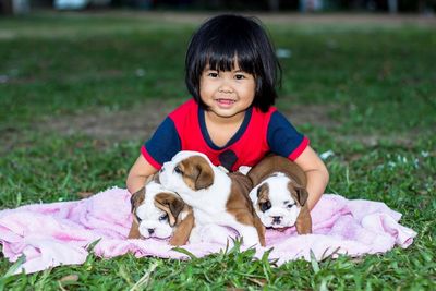 Portrait of cute girl with dogs sitting on grass