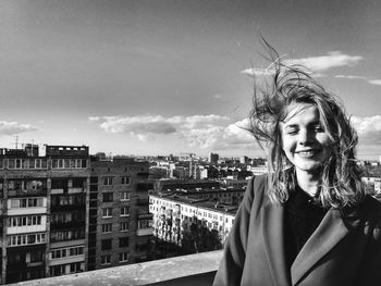 Portrait of beautiful woman against sky in city