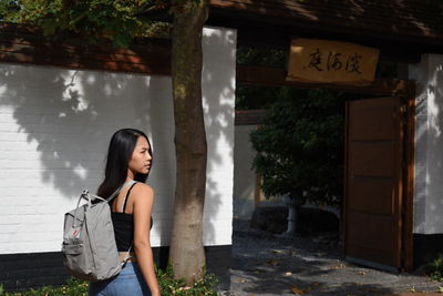 Portrait of young thai woman standing in front of gate.