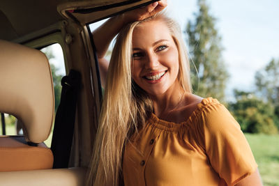 Portrait of smiling young woman sitting in car