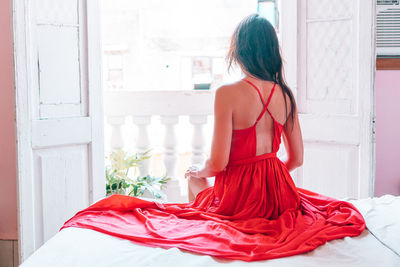 Rear view of woman with umbrella standing against window