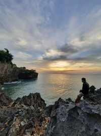 Man looking at sea against sky during sunset