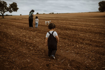 Rear view child walking on plowed field