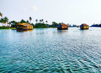 Boats sailing on river against clear sky