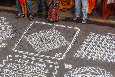 High angle view of people standing by rangolis on footpath during competition