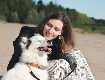 Happy laika dog smiling and sitting next to its owner. young beautiful woman stroking her dog 