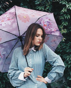 Beautiful woman standing with umbrella in rain