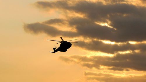 Low angle view of silhouette helicopter against sky during sunset