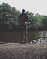 Rear view of man on lake against clear sky