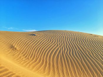 Sand dunes in desert against clear blue sky