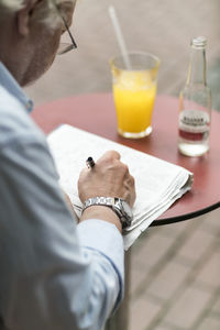 Senior man in a cafe writing on newspaper