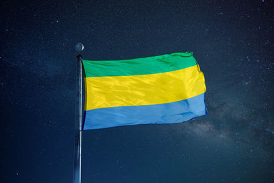 Low angle view of gabon flag against star field sky