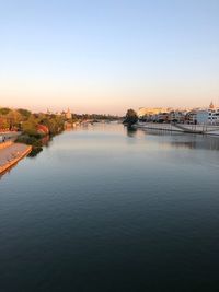 Scenic view of river by buildings against sky during sunset