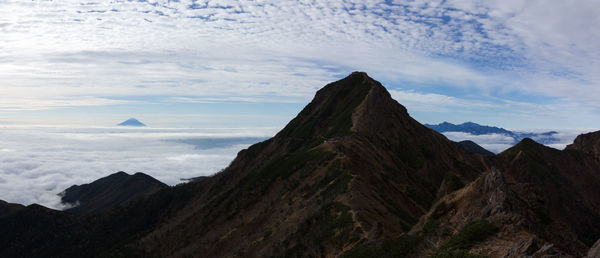 Scenic view of mountain range against cloudy sky