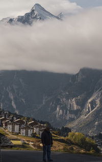 Rear view of man standing on mountain against sky