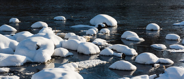 Scenic view of snow covered stones next to river 
