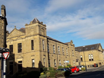 Cars on road by buildings against sky