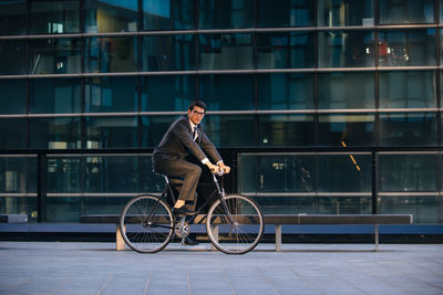 Man riding bicycle against building in city