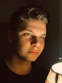 Close-up of man looking away by lamp at home