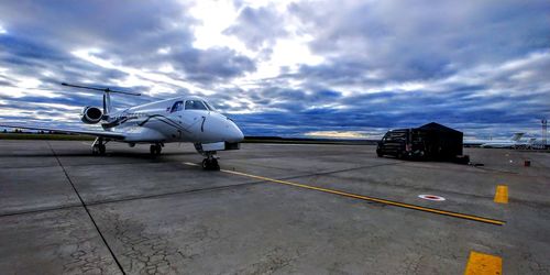 Airplane on airport runway against sky