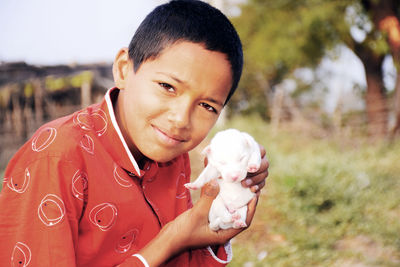 Portrait of boy holding camera on field