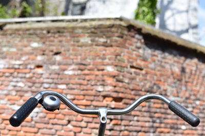 Low angle view of bicycle against brick wall