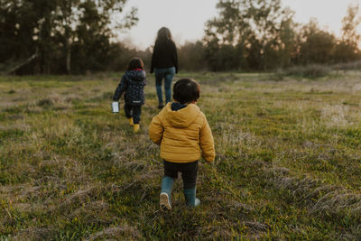 Rear view of mother and kids walking on grass