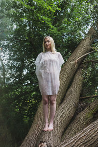 Full length of woman standing on tree trunk