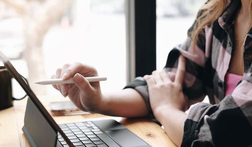 Midsection of woman using mobile phone while sitting on table